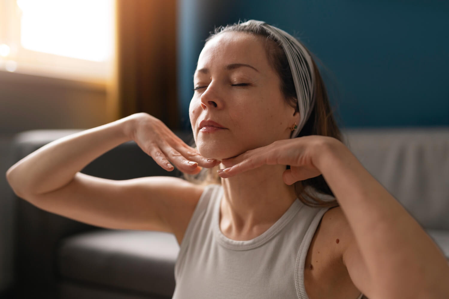 Mulher de olhos fechados tocando o contorno do rosto e pescoço, representando firmeza com bioestimuladores de colágeno em Feira de Santana.