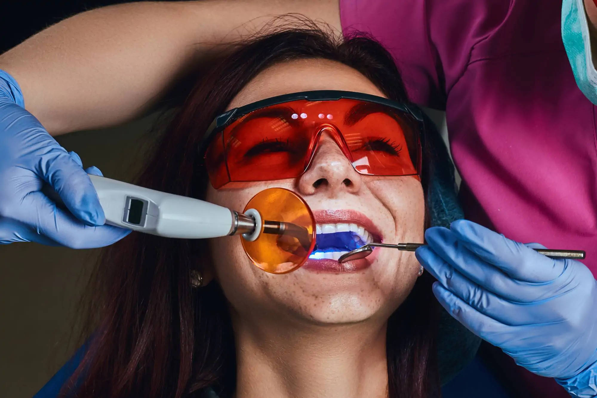 Paciente com óculos de proteção realizando clareamento dental a laser com a Dra. Camila Freitas em Feira de Santana.