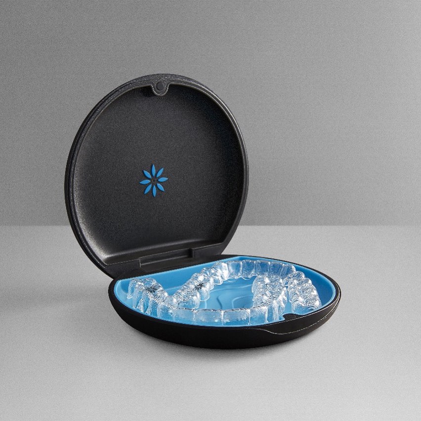 Estojo oficial Invisalign preto com interior azul contendo alinhadores invisíveis. Tecnologia ortodôntica disponível em Feira de Santana com Dra. Camila Freitas.