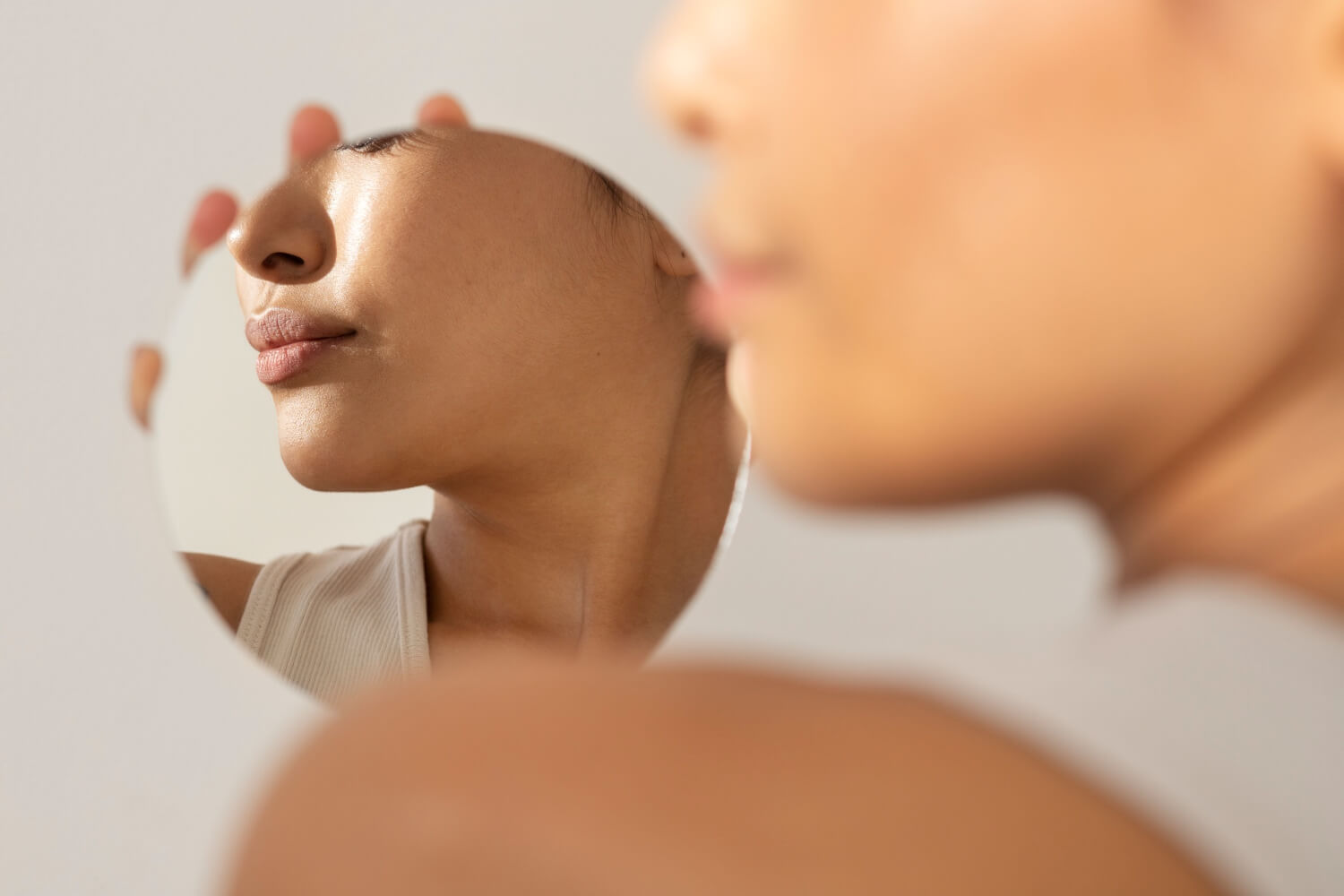 Close de rosto feminino refletido em pequeno espelho circular, destacando contornos para harmonização facial em Feira de Santana com Dra. Camila Freitas.