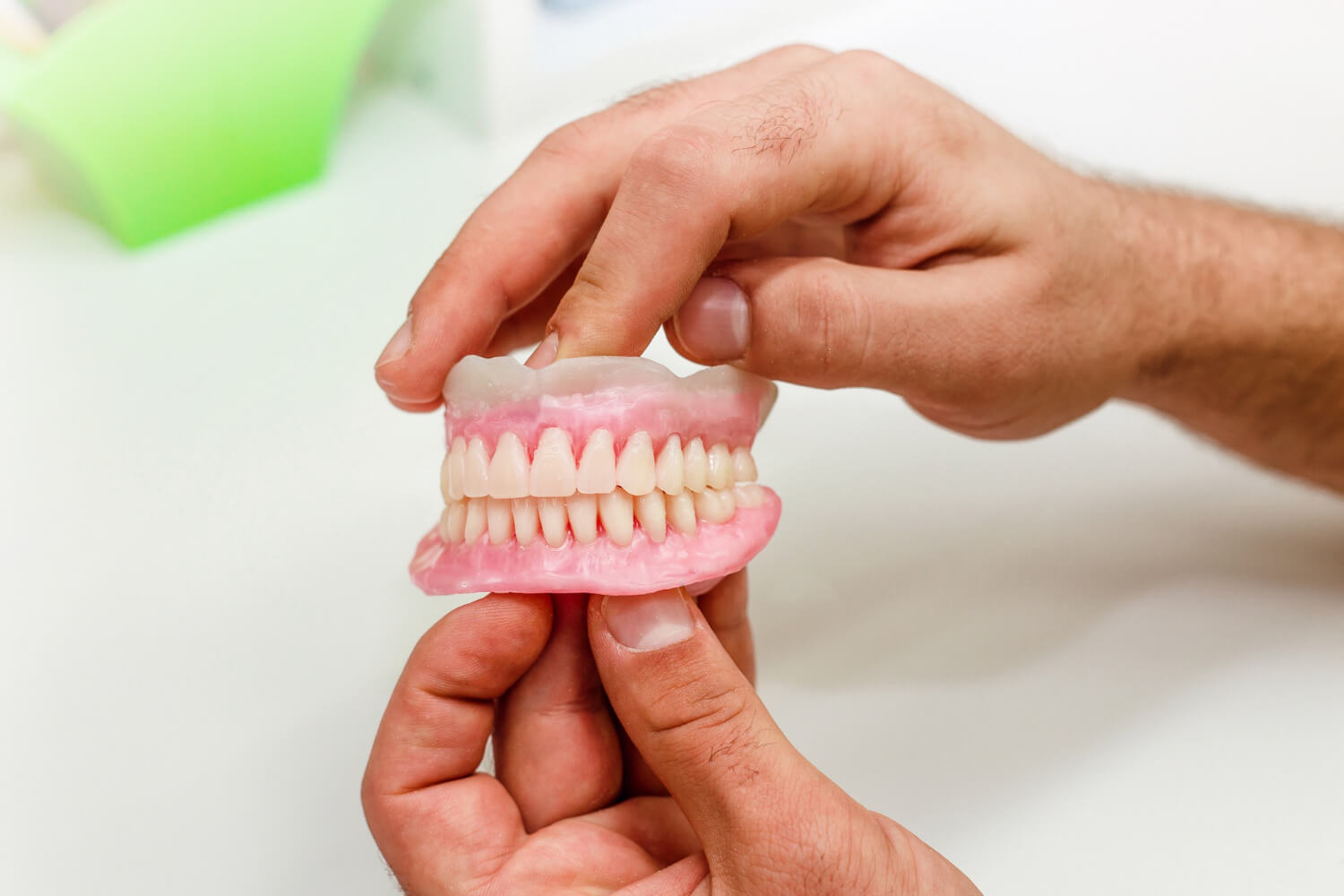 Especialista segurando modelo de prótese protocolo superior e inferior. Reabilitação oral com dentes fixos em Feira de Santana na Dra. Camila Freitas.