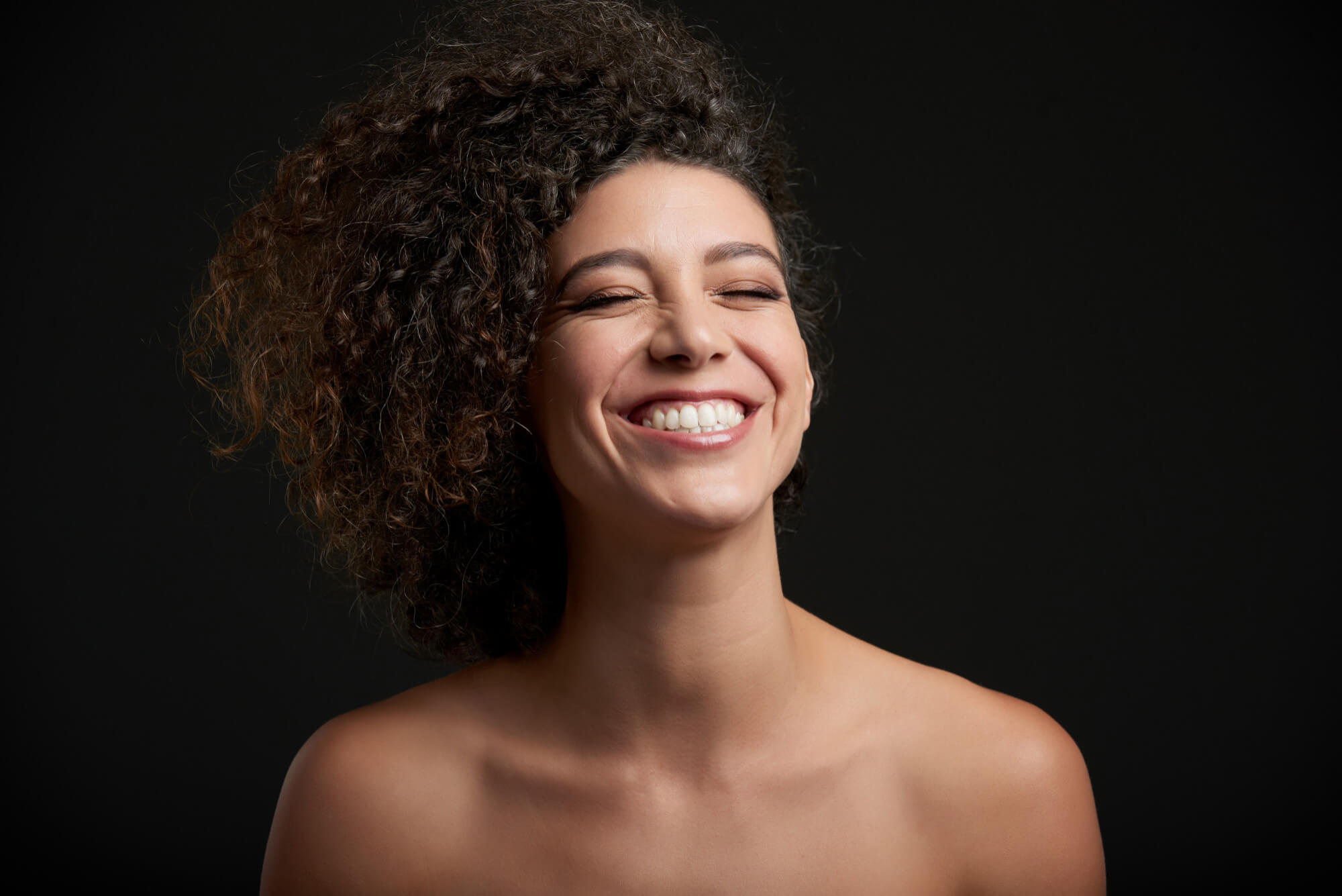 Mulher jovem sorrindo com dentes brancos e alinhados em destaque. Referência de atendimento com dentista em Feira de Santana na Dra. Camila Freitas. Especialista em Reabilitação Oral