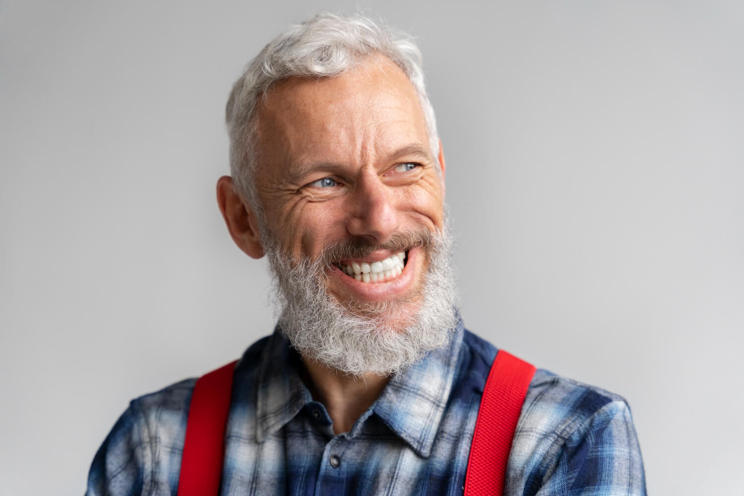 Homem sênior de barba grisalha sorrindo com dentes brancos e naturais após tratamento com prótese protocolo em Feira de Santana.