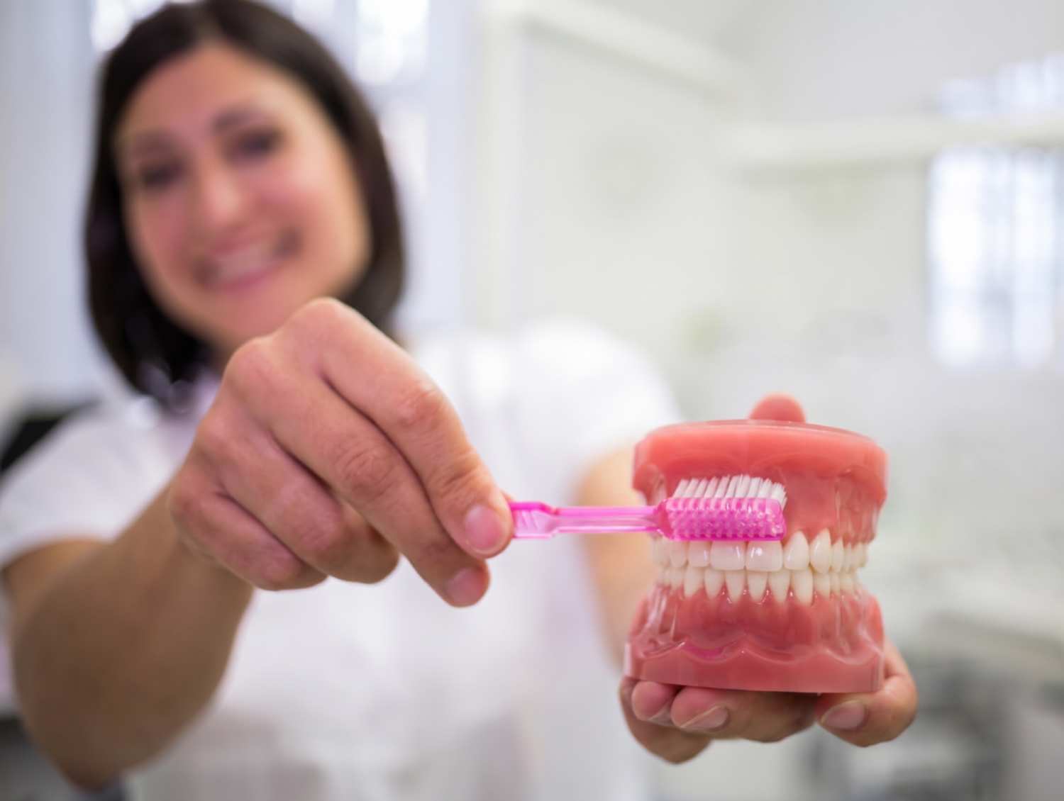 Dentista da Clínica Camila de Freitas ensina como higienizar a prótese protocolo no dia a dia usando modelo e escova em Feira de Santana.